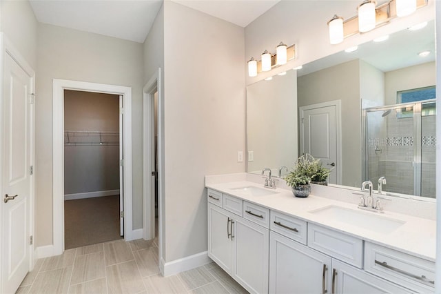 bathroom with double vanity, a shower stall, a spacious closet, and a sink