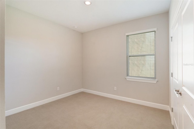 spare room with light carpet and baseboards