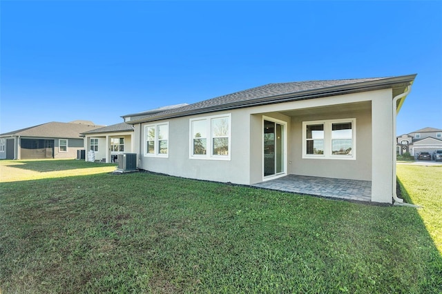 rear view of house with roof with shingles, a yard, a patio, stucco siding, and cooling unit