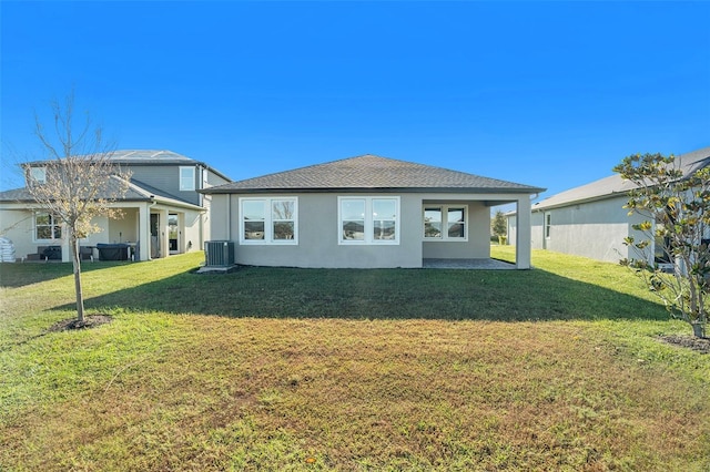 back of property featuring central AC, a lawn, and stucco siding