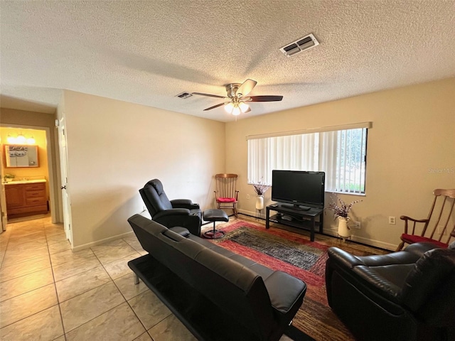 living room featuring ceiling fan, light tile patterned flooring, and a textured ceiling