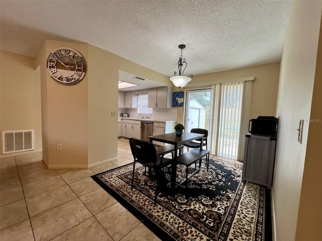 dining space featuring light tile patterned floors, baseboards, visible vents, and a textured ceiling