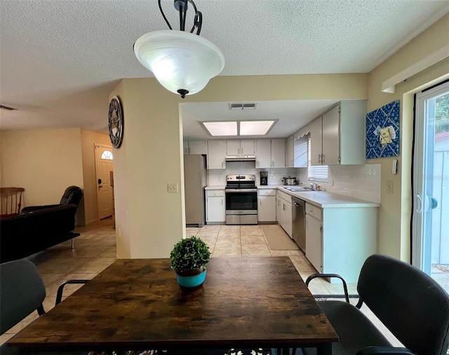 kitchen with white cabinets, sink, decorative backsplash, light tile patterned floors, and stainless steel appliances