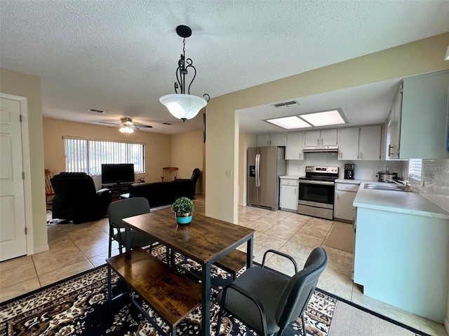 dining room featuring ceiling fan, sink, light tile patterned floors, and a textured ceiling