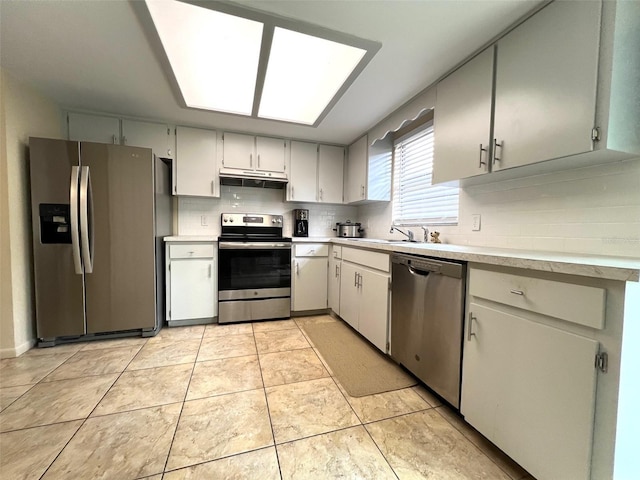 kitchen with backsplash, sink, light tile patterned floors, appliances with stainless steel finishes, and white cabinetry