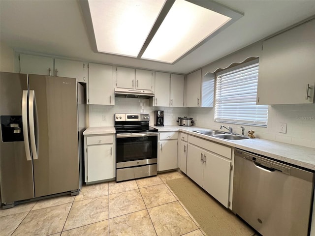 kitchen with appliances with stainless steel finishes, white cabinetry, light tile patterned floors, and sink