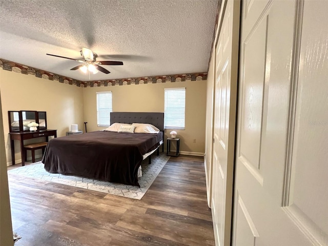 bedroom with ceiling fan, wood finished floors, baseboards, and a textured ceiling