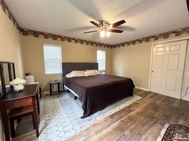 bedroom with a textured ceiling, a ceiling fan, baseboards, and wood finished floors