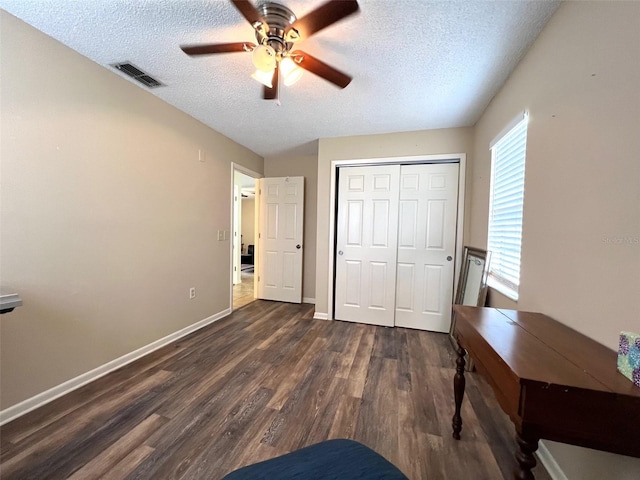 unfurnished bedroom featuring dark wood-type flooring, visible vents, a closet, and a textured ceiling