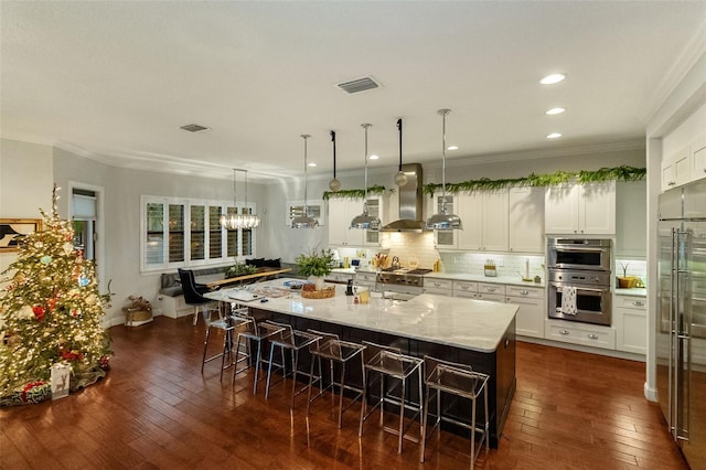 kitchen featuring appliances with stainless steel finishes, white cabinetry, a kitchen breakfast bar, a large island, and light stone counters