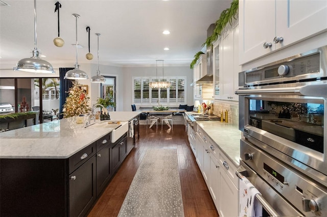 kitchen with pendant lighting, white cabinetry, sink, a kitchen island with sink, and light stone countertops