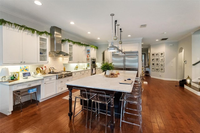 kitchen featuring stainless steel appliances, a center island, white cabinets, and wall chimney exhaust hood