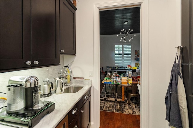 kitchen with dark brown cabinetry, dark hardwood / wood-style flooring, a chandelier, and sink