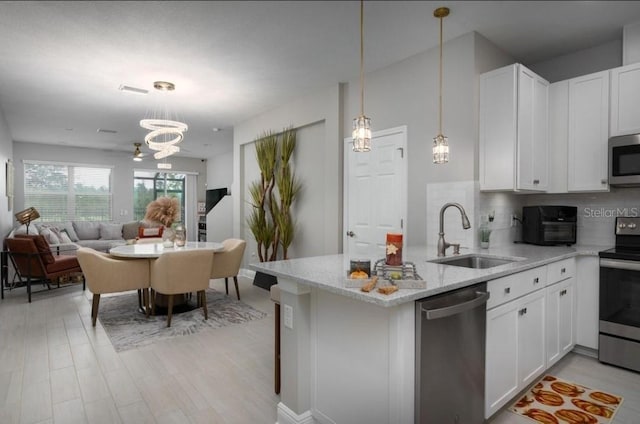 kitchen with tasteful backsplash, sink, white cabinets, and appliances with stainless steel finishes