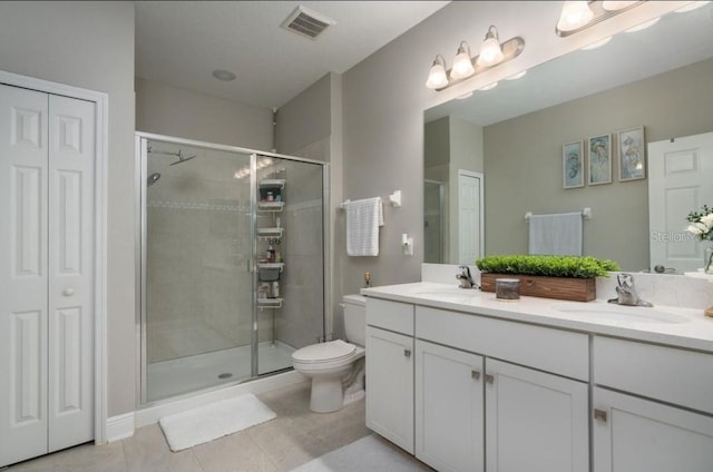 bathroom featuring toilet, vanity, tile patterned floors, and a shower with door