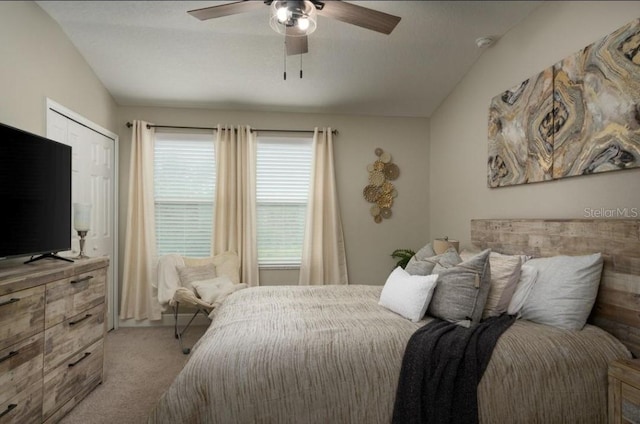 bedroom featuring a closet, light colored carpet, vaulted ceiling, and ceiling fan