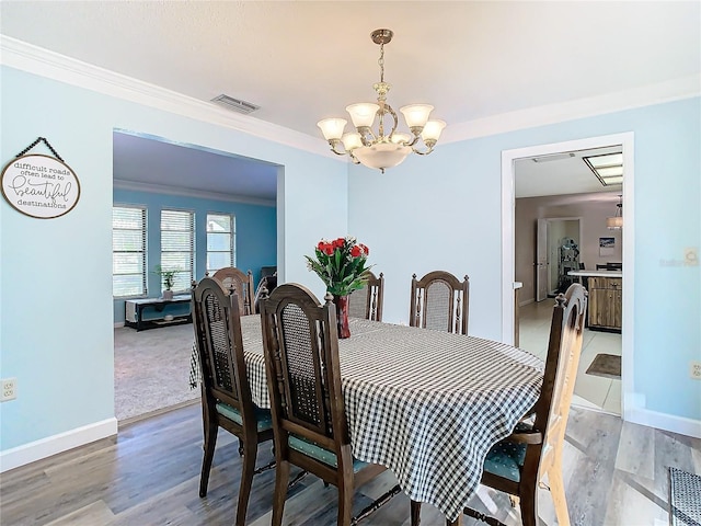 dining space featuring ornamental molding, wood-type flooring, and a notable chandelier