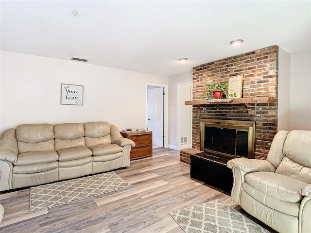 living room with light hardwood / wood-style floors and a brick fireplace