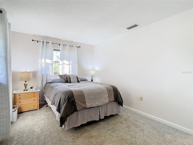 bedroom with light colored carpet and a textured ceiling