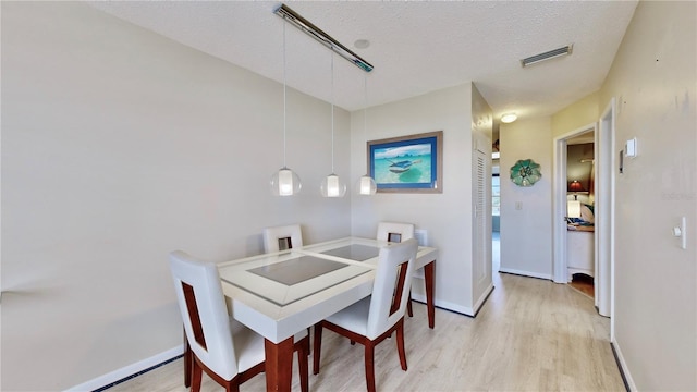 dining area with light hardwood / wood-style floors and a textured ceiling