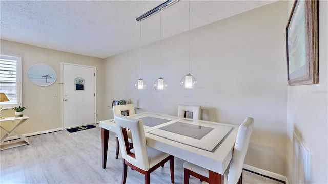 dining room with a textured ceiling and light wood-type flooring