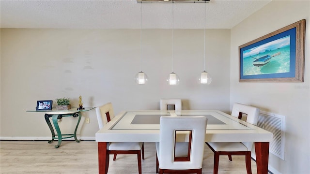 dining space with hardwood / wood-style floors and a textured ceiling