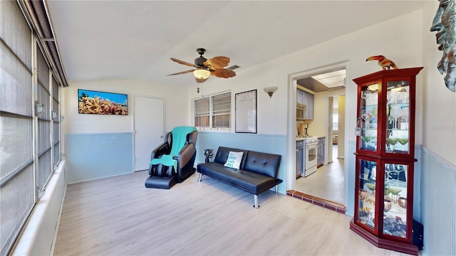 living area with ceiling fan, light hardwood / wood-style floors, and vaulted ceiling