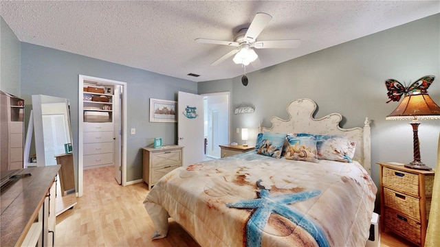 bedroom with ceiling fan, light hardwood / wood-style flooring, and a textured ceiling