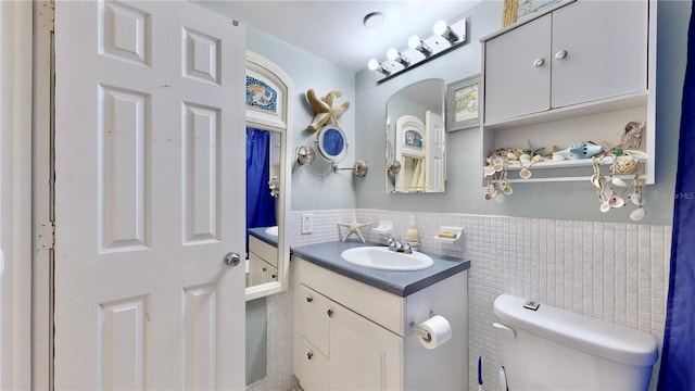 bathroom with vanity, toilet, and tile walls