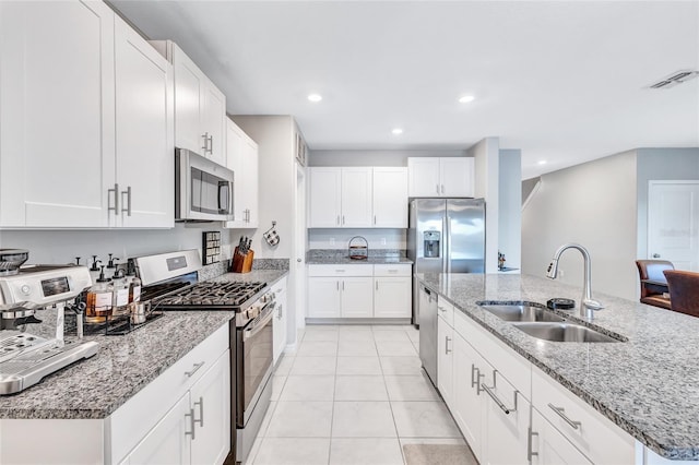 kitchen with appliances with stainless steel finishes, sink, white cabinetry, and an island with sink