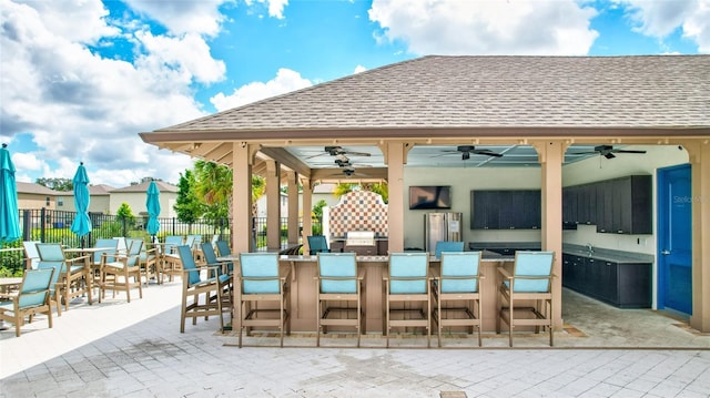 view of patio featuring ceiling fan and a bar