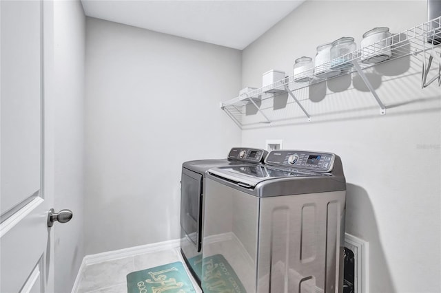 washroom with laundry area, washing machine and dryer, light tile patterned floors, and baseboards