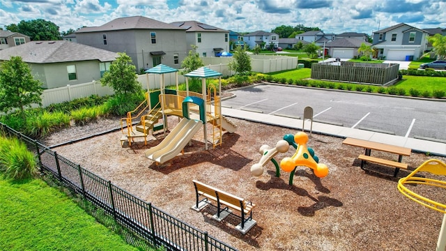 community jungle gym with a residential view, fence, and a lawn