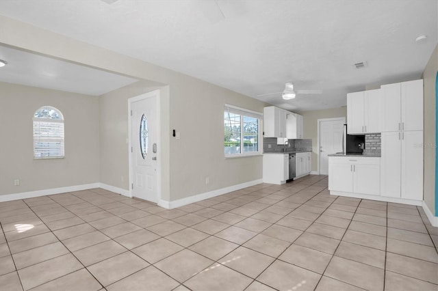 kitchen featuring ceiling fan, dishwasher, light tile patterned floors, backsplash, and white cabinets