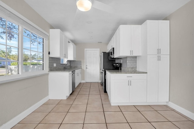 kitchen with white cabinets, backsplash, light stone countertops, and stainless steel appliances