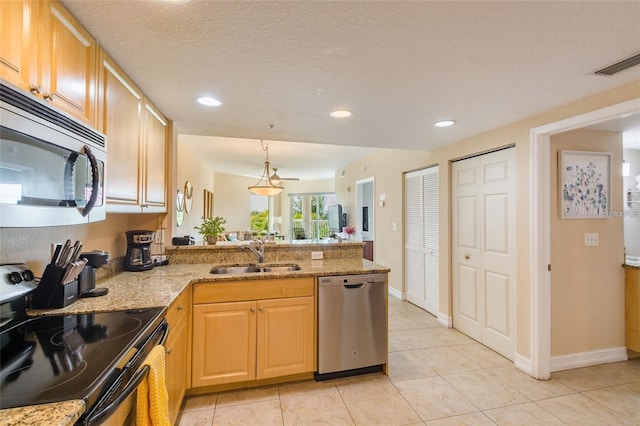 11605 Gulf Blvd Unit 307, Saint Petersburg, FL 33706 - kitchen featuring stainless steel appliances, a peninsula, light stone countertops, light tile patterned floors, and recessed lighting