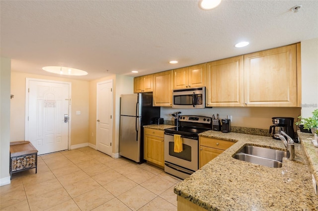 kitchen with sink, light brown cabinets, light stone counters, light tile patterned floors, and appliances with stainless steel finishes