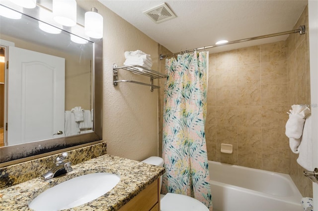 full bathroom with shower / bath combo with shower curtain, vanity, a textured ceiling, and toilet