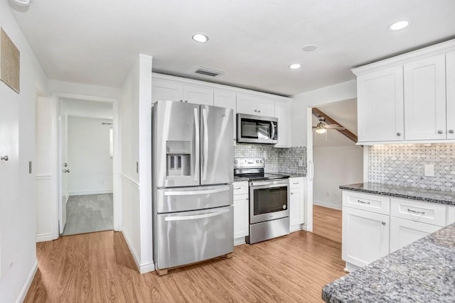 kitchen featuring dark stone counters, white cabinetry, light hardwood / wood-style floors, and appliances with stainless steel finishes