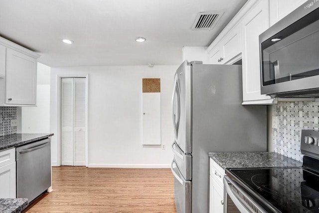 kitchen with decorative backsplash, appliances with stainless steel finishes, dark stone counters, light hardwood / wood-style floors, and white cabinetry