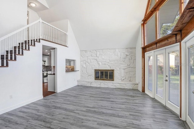 unfurnished living room featuring lofted ceiling, dark wood-type flooring, a fireplace, and french doors