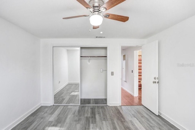 unfurnished bedroom featuring hardwood / wood-style flooring, ceiling fan, and a closet