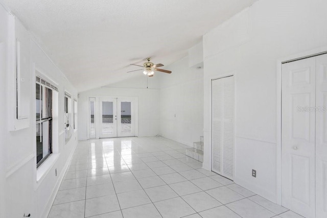 unfurnished living room with ceiling fan, light tile patterned flooring, french doors, and vaulted ceiling