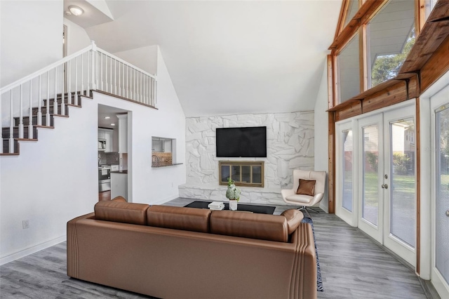 living room with french doors, a stone fireplace, lofted ceiling, and hardwood / wood-style floors