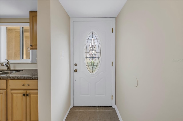 entryway with light tile patterned flooring, a sink, and baseboards