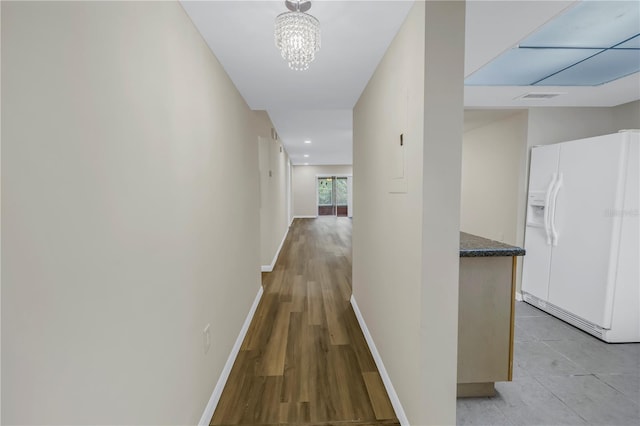 hall featuring a chandelier, visible vents, and baseboards