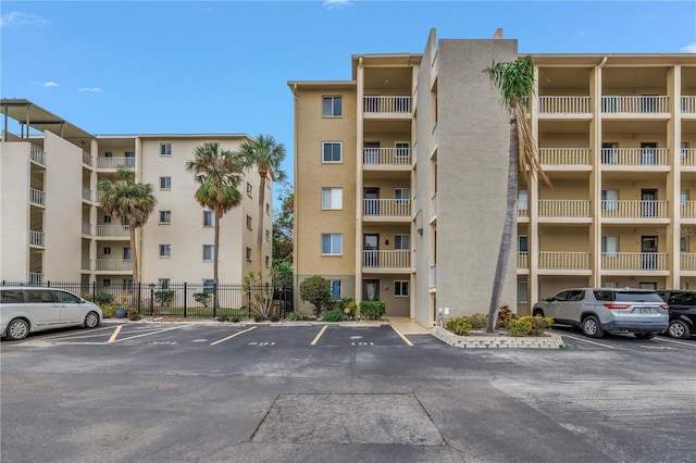 view of property with uncovered parking and fence