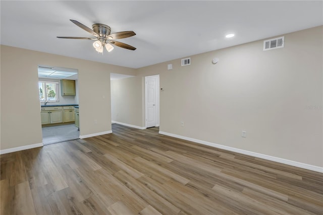 spare room featuring light wood-type flooring, baseboards, visible vents, and ceiling fan