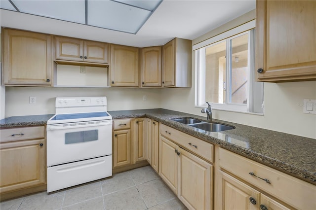 kitchen with light tile patterned floors, light brown cabinets, electric range, a sink, and dark stone counters