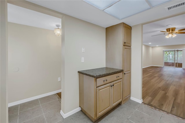 kitchen with visible vents, baseboards, open floor plan, light brown cabinetry, and dark countertops